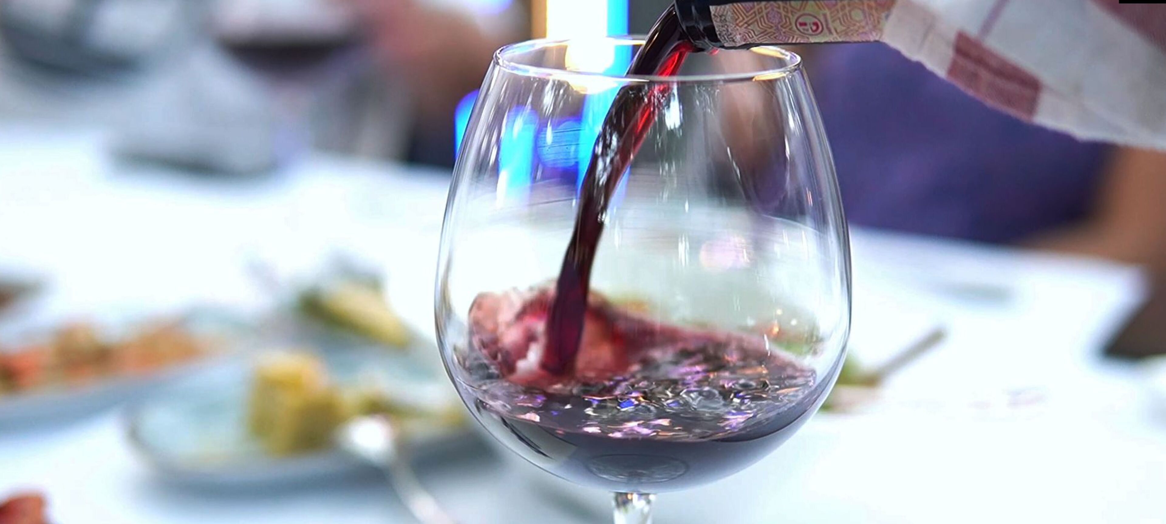 Una copa de vino siendo servida con vino tinto.