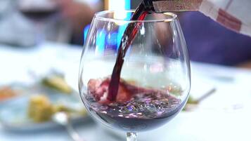 Una copa de vino siendo servida con vino tinto.