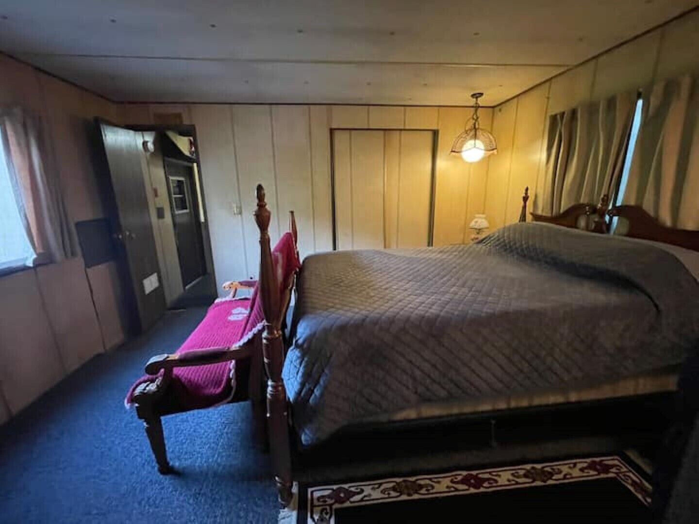 A bedroom with a bed, a chair, a wardrobe, and a door.
