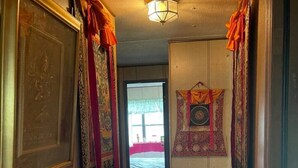Un couloir avec des rideaux à motifs, un plancher en bois et un luminaire au plafond.