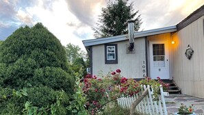 Une petite maison à un seul étage, avec une clôture blanche en bois, une boîte aux lettres et le numéro « 2086 » sur la porte.