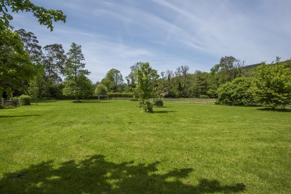 A spacious grassy area with trees and a fence.