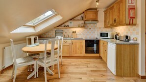 A kitchen with wooden cabinets, a microwave, a stove, and a dishwasher. There is a skylight above the kitchen counter. - Bilbrook Cottage, Near Dunster (Dunster)