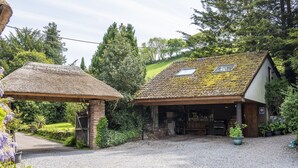 A rustic building with a thatched roof and a tiled roof, surrounded by greenery. - Bilbrook Cottage, Near Dunster (Dunster)