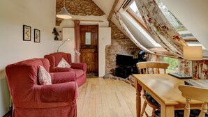 A cozy living room with a stone ceiling, a wooden dining table, and a red sofa.