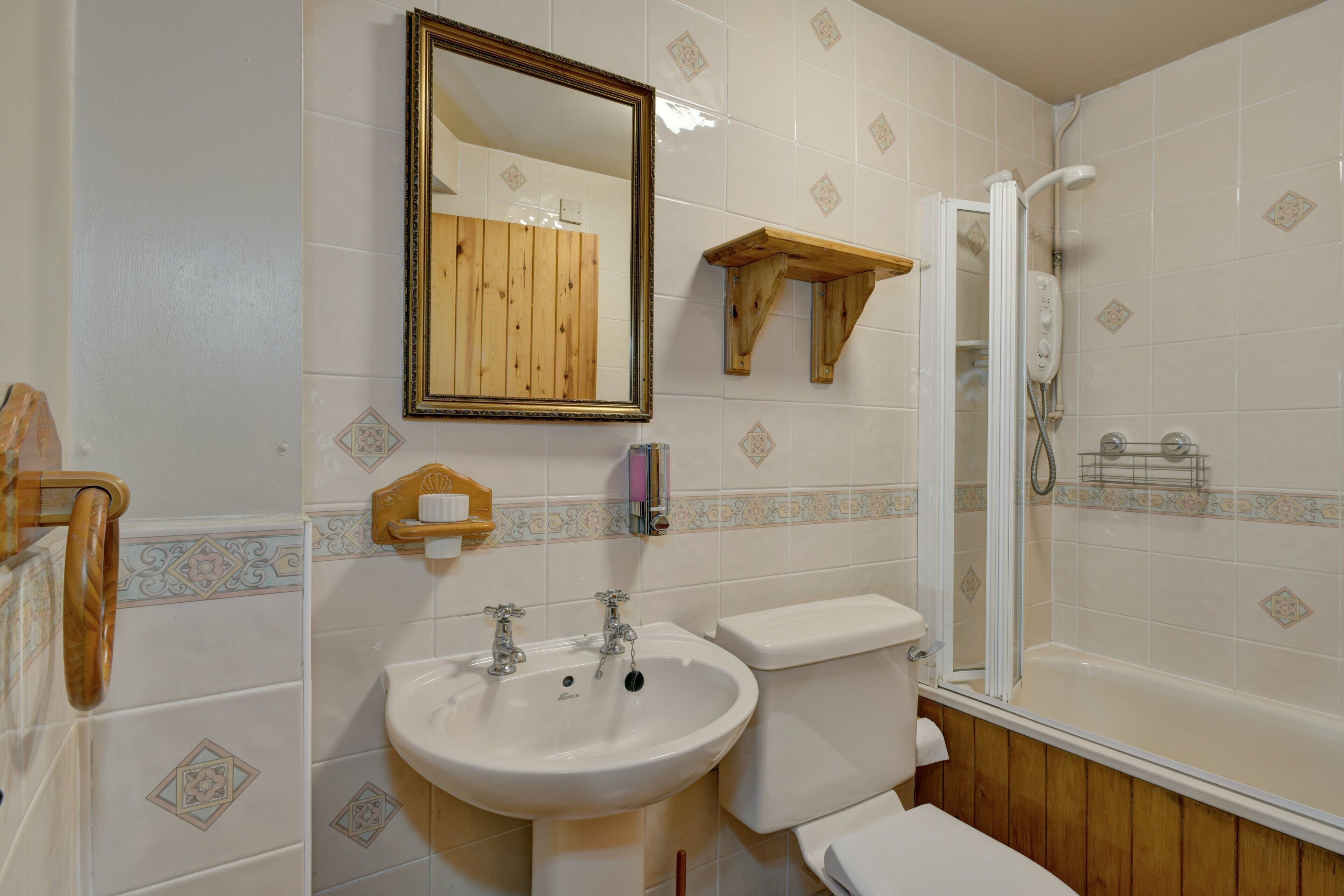 Une salle de bain avec un meuble-lavabo en bois, un évier, des toilettes et une douche.