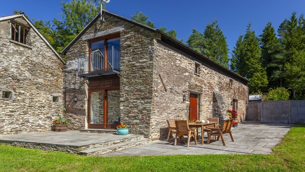 A stone building with a balcony, a patio with a table and chairs, and a garden area. - Red Deer Cottage, Wheddon Cross (Wheddon Cross)