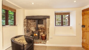 A cozy room with a stone fireplace, a leather sofa, and a wooden door. - Hedgehog Cottage, Wheddon Cross (Wheddon Cross)