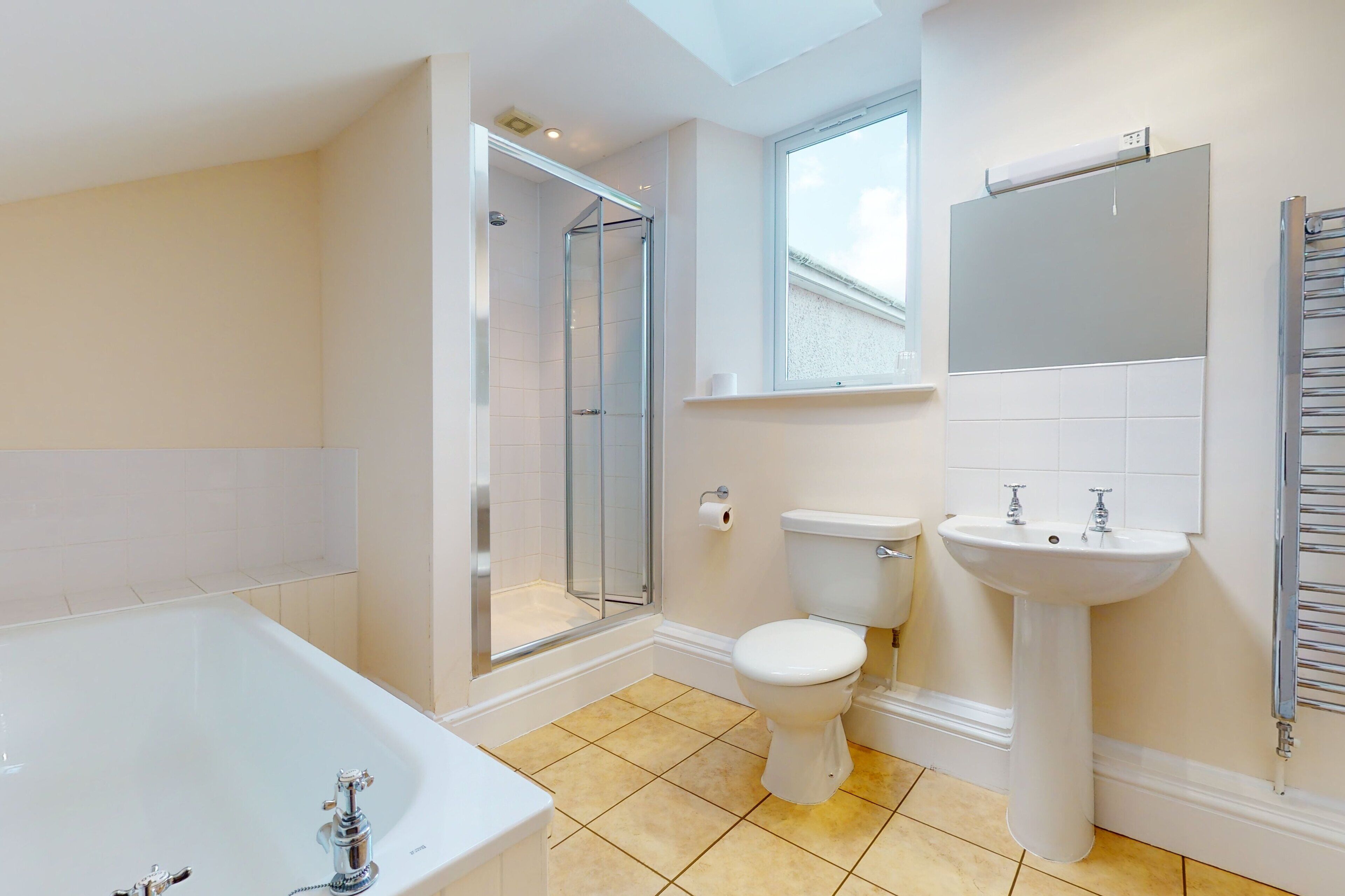 A modern bathroom with a bathtub, toilet, and shower.