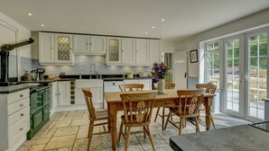 A modern kitchen with white cabinets, a wooden dining table, and chairs. - The Farmhouse, West Anstey (West Anstey)