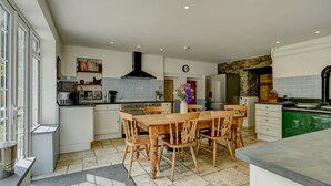 A spacious kitchen with a central island, wooden chairs, and a dining table. - The Farmhouse, West Anstey (West Anstey)
