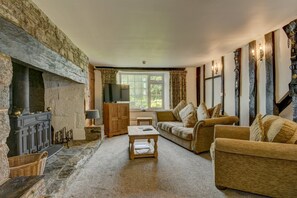 A cozy living room with a stone fireplace, a television, a sofa, and a coffee table.