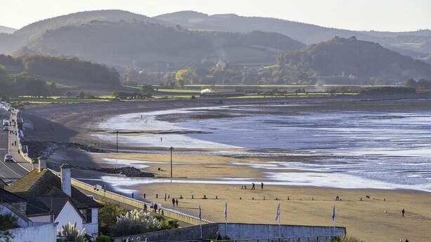 A coastal beach with a road leading to a building with a sloped roof. - Pine in Cleeve Park Near Blue Anchor (Near Blue Anchor)