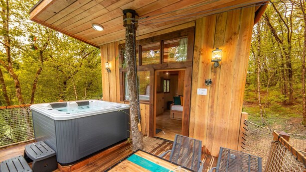 Una cabaña de madera con hidromasaje, piscina y zona de terraza.