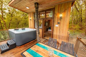 Une cabane en bois dotée d’un bain à remous, d’une piscine et d’une terrasse.
