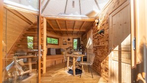 Una cabaña de madera acogedora con comedor, cocina y un amplio ventanal.