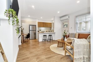 A modern apartment with a kitchen, dining area, and living room. - Glenelg Stay at The Bay (Glenelg South)