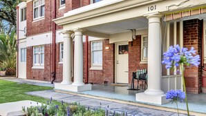 A two-story brick building with a covered porch and a number '101' sign. - Glenelg Stay at The Bay (Glenelg South)