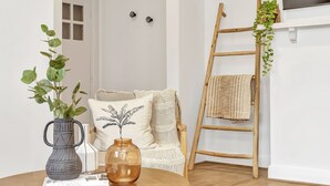 A cozy room with a wooden table, a white door, a white chair, and a wooden ladder with a hanging plant. - Glenelg Stay at The Bay (Glenelg South)