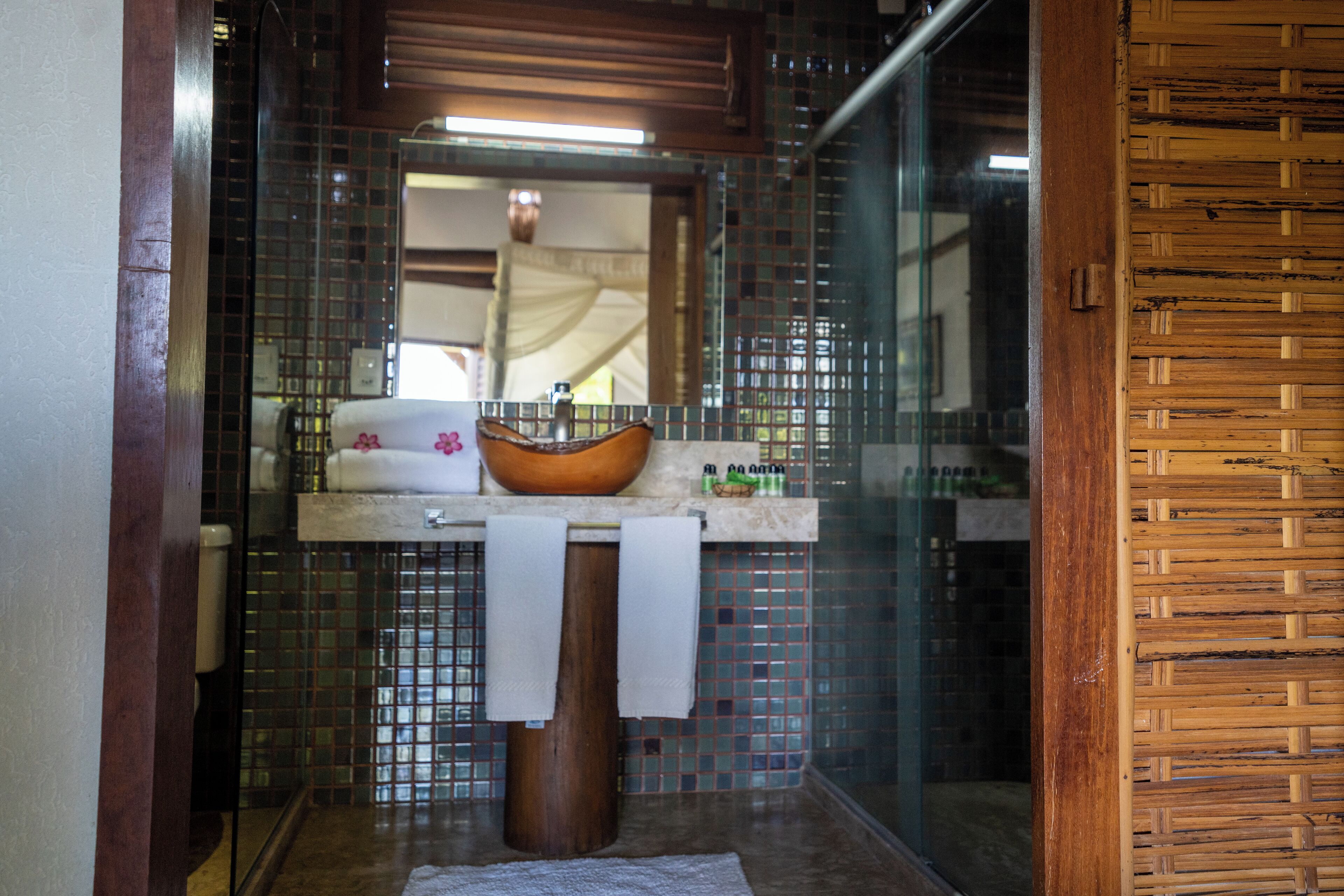 A bathroom with a wooden vanity, a large mirror, and a mosaic tile backsplash.