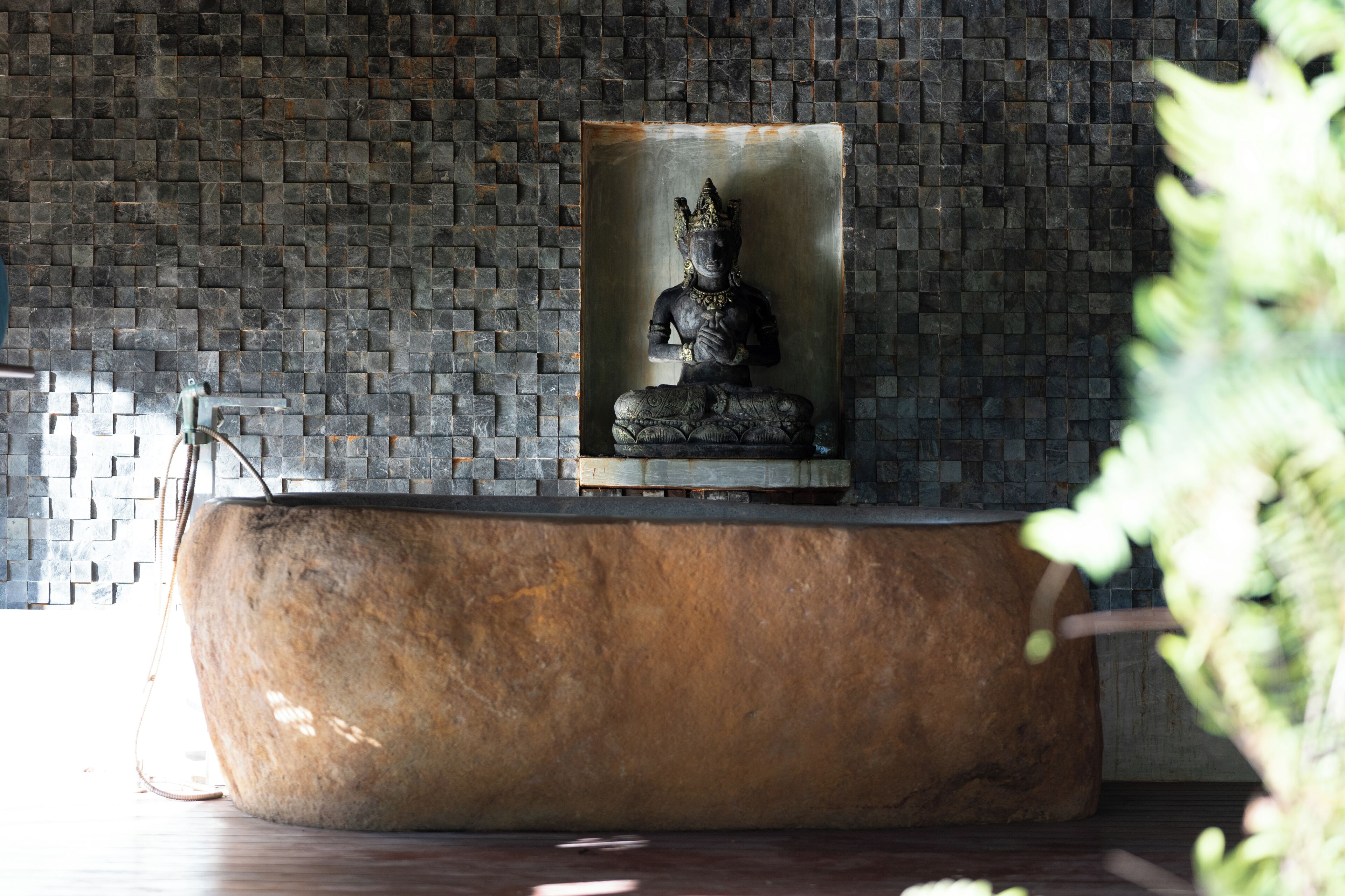 A stone statue on a pedestal in a room with a brick wall.