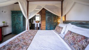A spacious bedroom with a large bed, a canopy bed, and a view of a bathroom with a sink and mirror. - Hotel Villa Balidendê (Maraú)