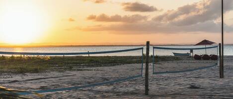 Una red de voleibol de playa con un poste de red y un farol al fondo.