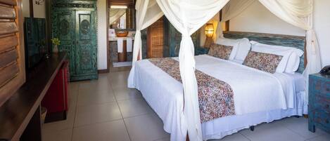 A room with a four-poster bed, a wooden cabinet, and a red bench.