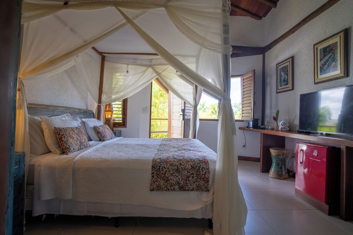 Un dormitorio con cama a dosel, televisión y un refrigerador pequeño.