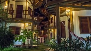 A multi-story building with a unique spiral staircase design, illuminated by warm lighting. - Hotel Villa Balidendê (Maraú)
