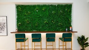 A reception area with a green wall, three green bar stools, a wooden counter, and a framed map on the wall. - Beautiful Aparment in Psiri-Monastiraki (Athens)