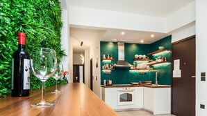 A modern kitchen with a green accent wall, white cabinets, and a wooden countertop. - Beautiful Aparment in Psiri-Monastiraki (Athens)