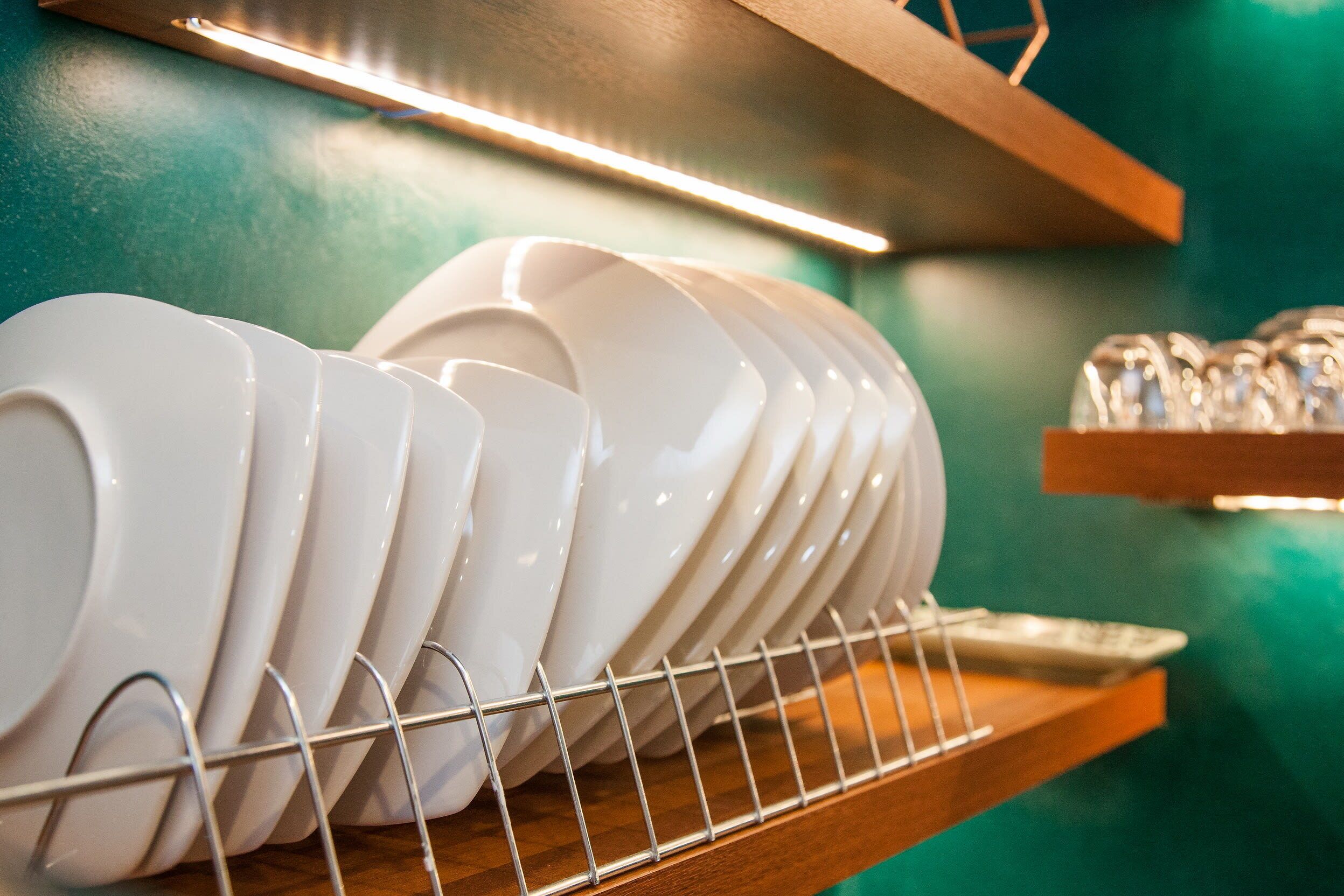 A rack of white plates and bowls on a wooden shelf.