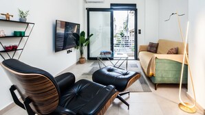 A modern living room with a sofa, two leather chairs, a TV, a plant, and a floor lamp. - Beautiful Aparment in Psiri-Monastiraki (Athens)