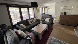 Moderni olohuone, jossa on sohva, sohvapöytä sekä ruokailutila tuoleineen ja pöytineen.