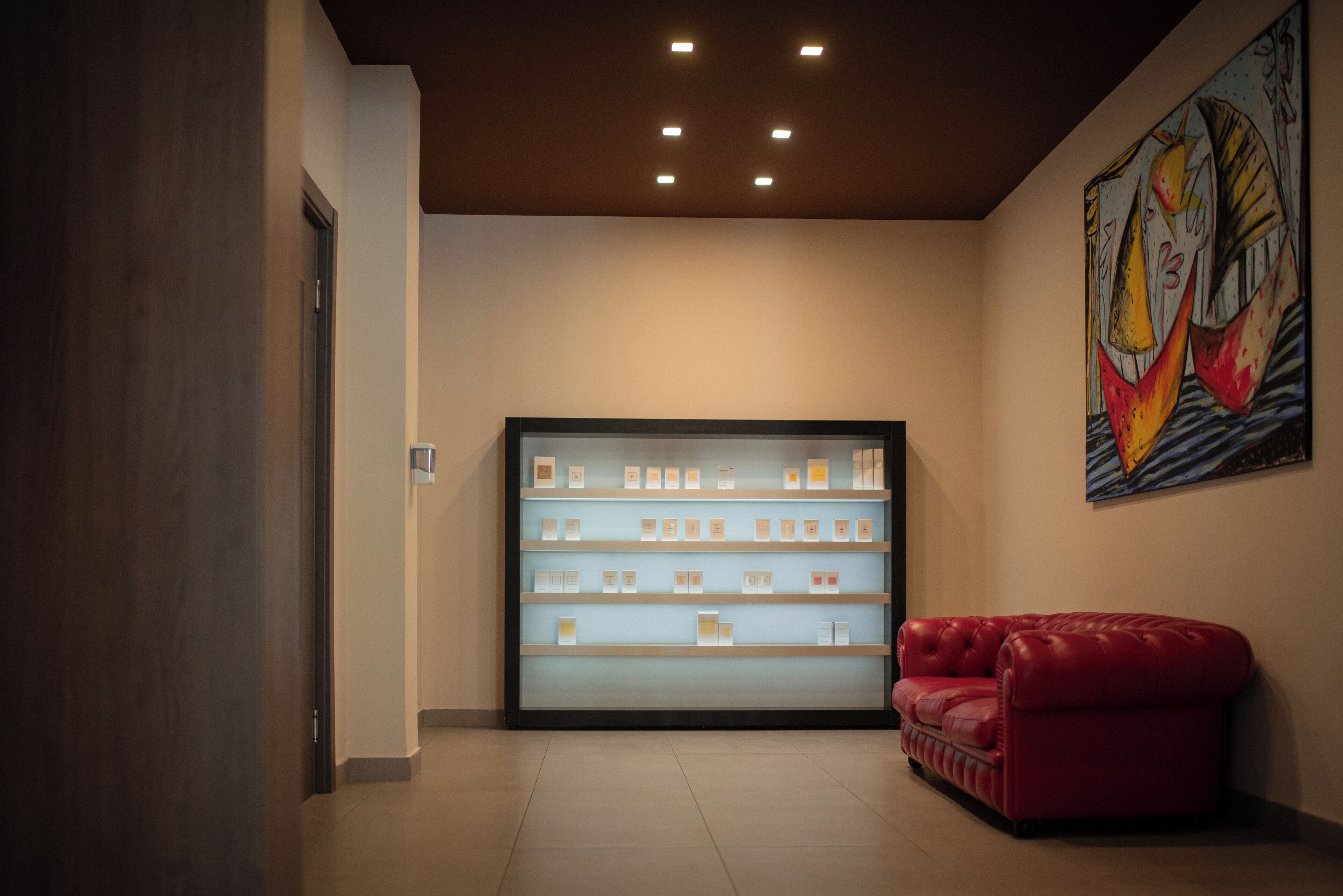 A lobby with a display case of products, a red leather sofa, and a colorful abstract painting on the wall.