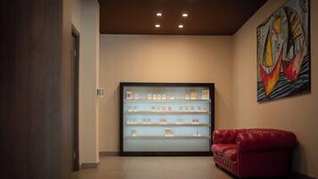 A lobby with a display case of products, a red leather sofa, and a colorful abstract painting on the wall.