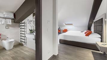 Un dormitorio moderno con una cama grande, una mesita de noche y un baño con bidé y perchero para toallas.