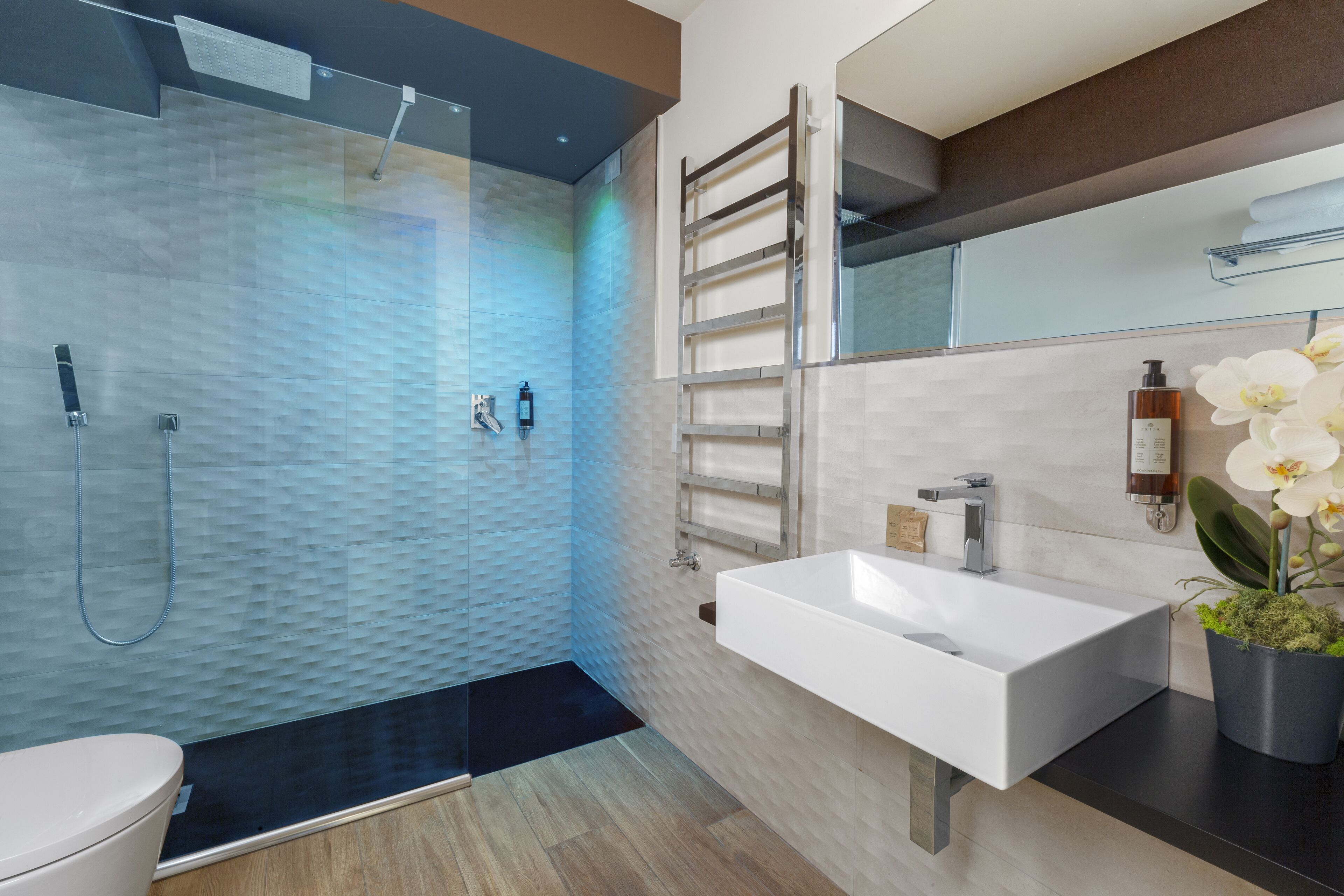 A modern bathroom with a glass-enclosed shower, a white sink, and a mirror above it.