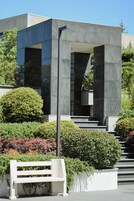 A modern building with a minimalist design, featuring a large glass entrance and a series of steps leading up to it.
