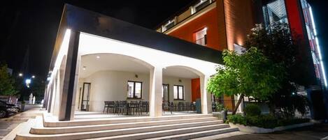 A modern hotel with a covered outdoor seating area and a staircase leading to the entrance.