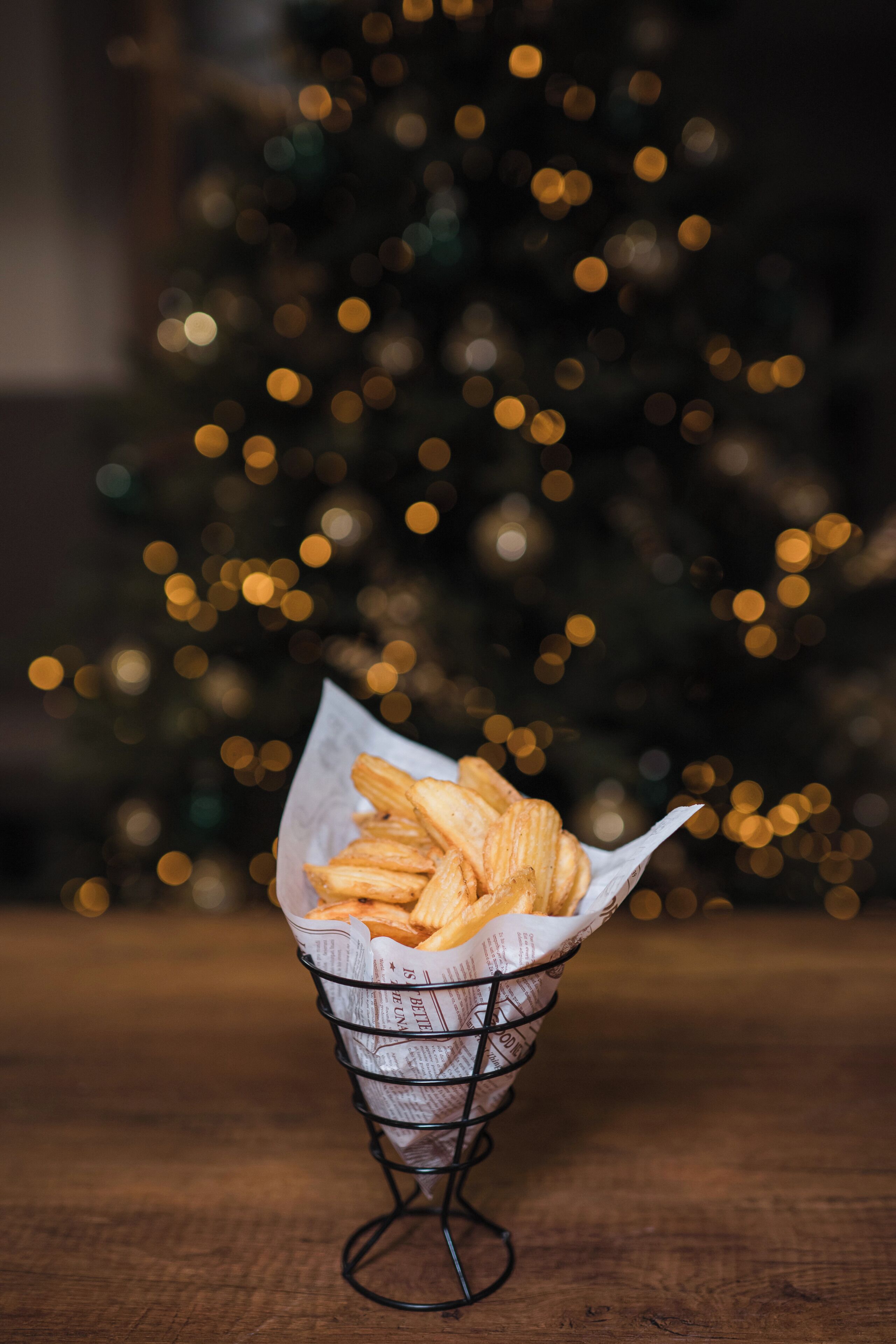 Un panier de frites sur une table, avec un sapin de Noël flou en arrière-plan.