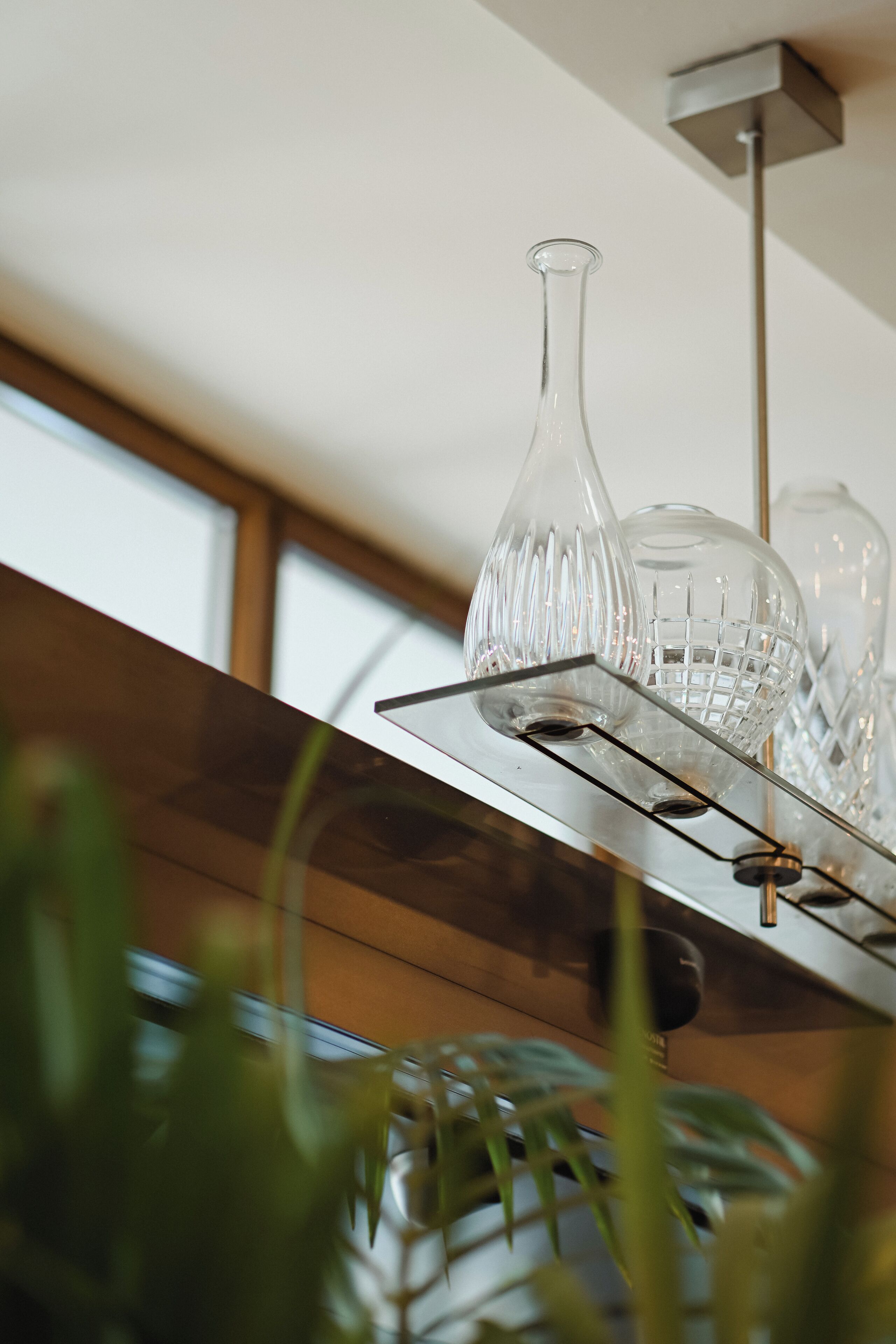 Una cucina moderna con uno scaffale in acciaio inossidabile pieno di bicchieri e un lampadario.
