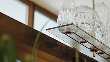 Una cucina moderna con uno scaffale in acciaio inossidabile pieno di bicchieri e un lampadario.