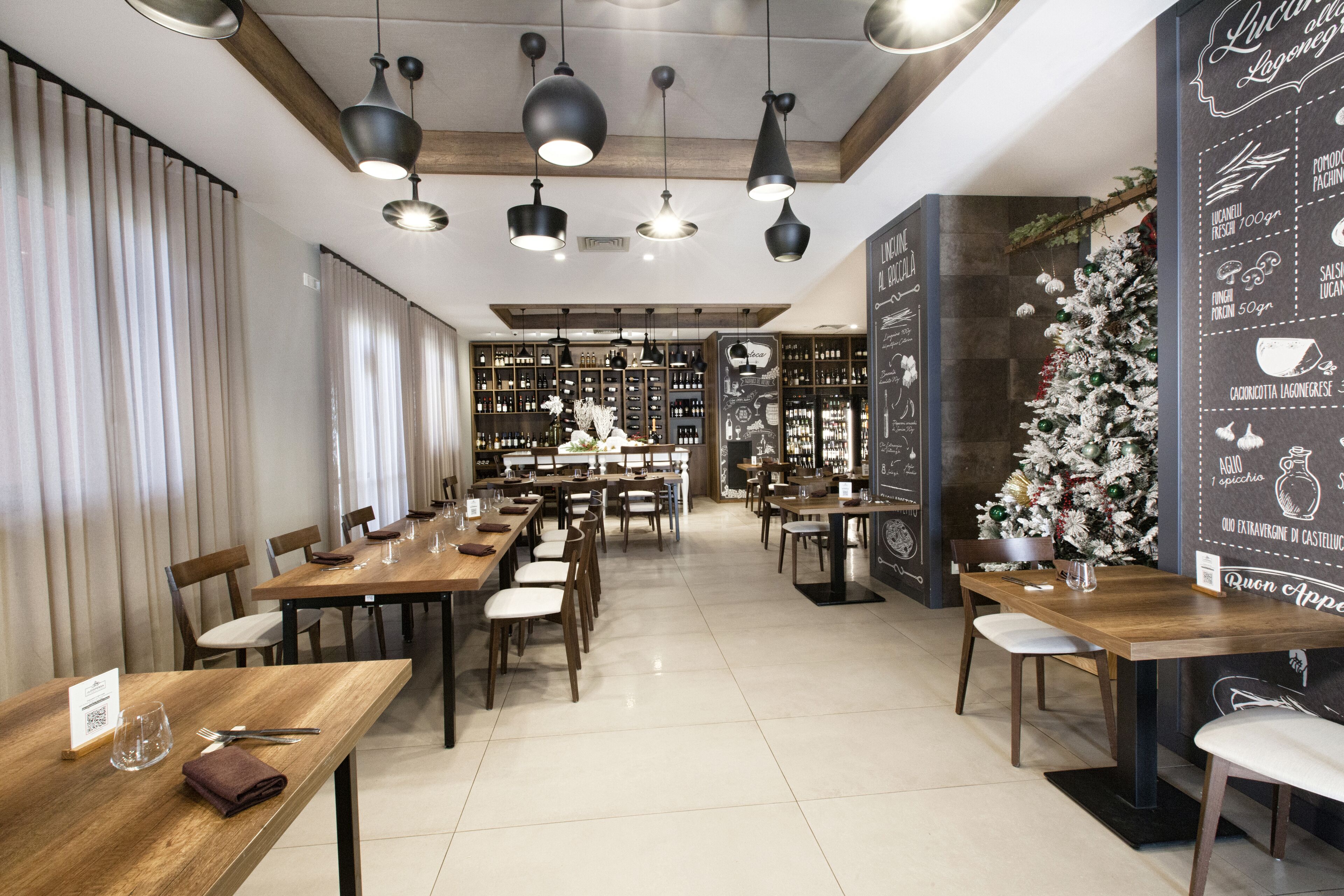 A restaurant with wooden tables and chairs, hanging pendant lights, and a Christmas tree.