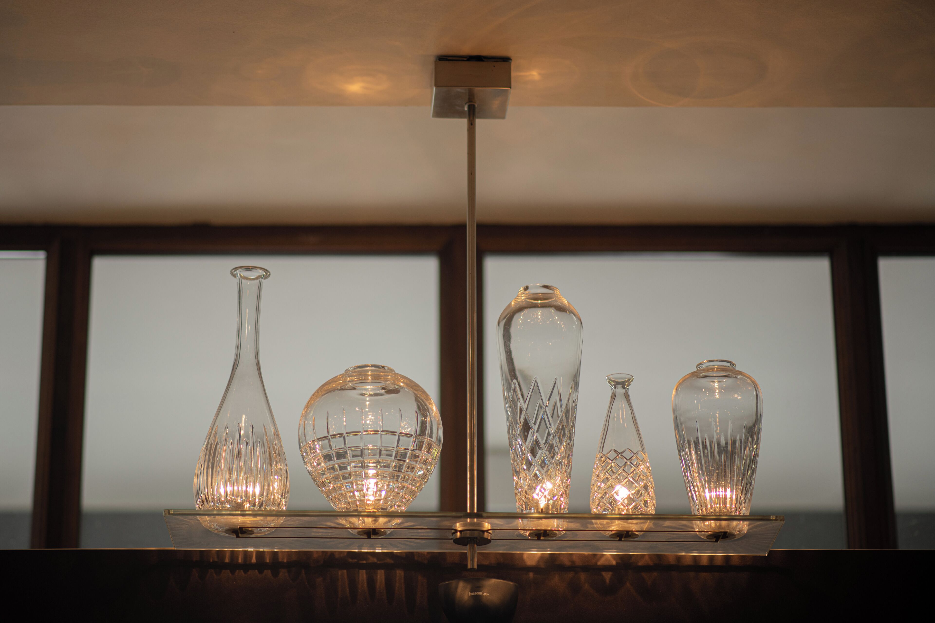 A chandelier with four glass vases on a reflective surface.