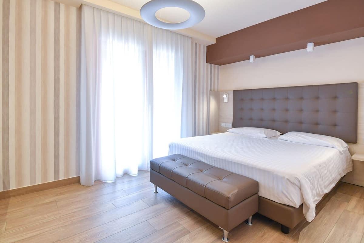 Un dormitorio moderno con una cama grande, un banco y una lámpara en el techo.