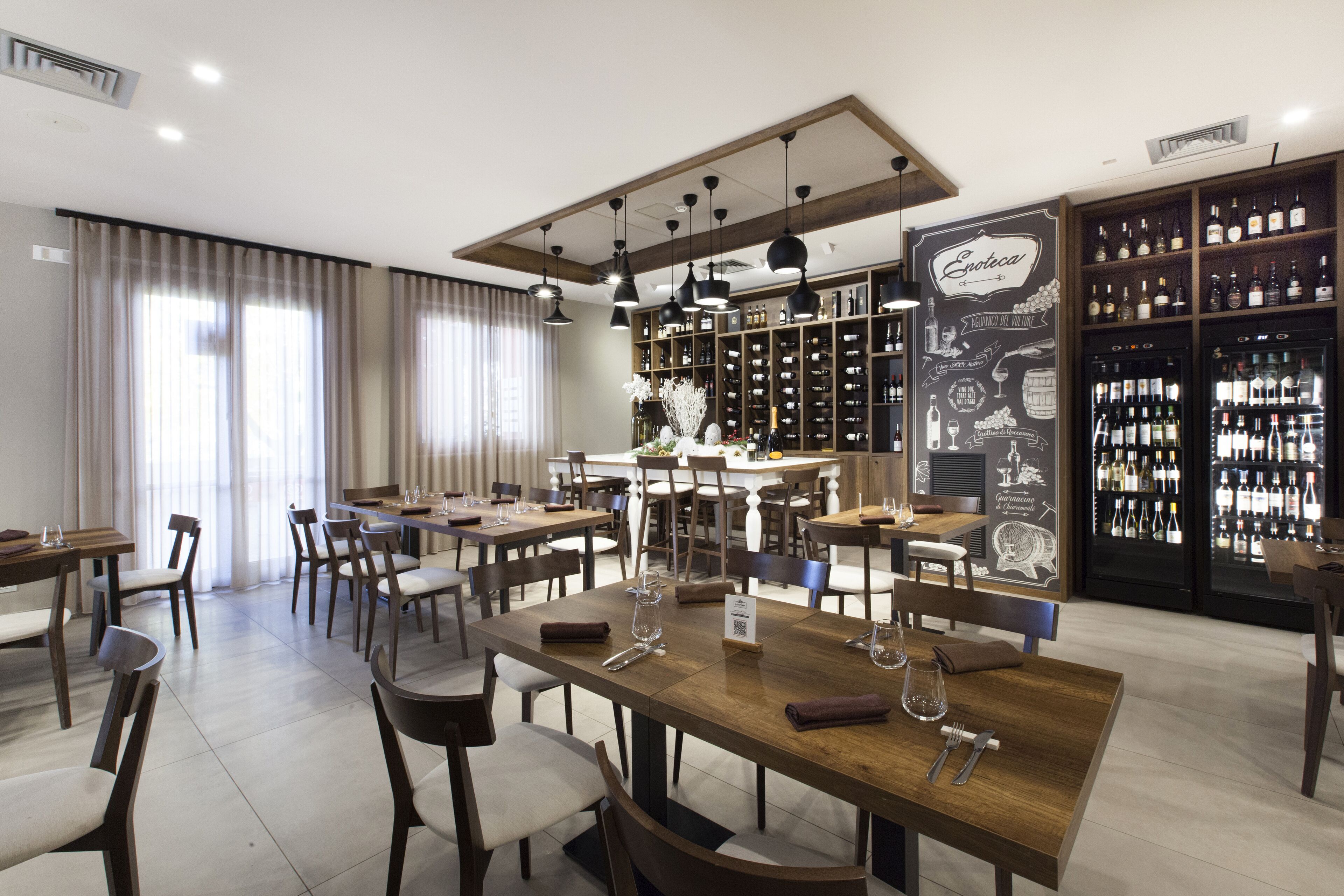 Ein geräumiger Essbereich mit mehreren Tischen und Stühlen, eine Weinkellerei und eine Bar.