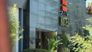 A modern hotel exterior with a glass facade, a sign reading "HOTEL", and outdoor seating. - BHotel (Lagonegro)