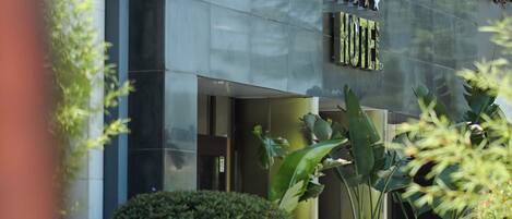Exterior de un hotel moderno con fachada de vidrio, un letrero que dice